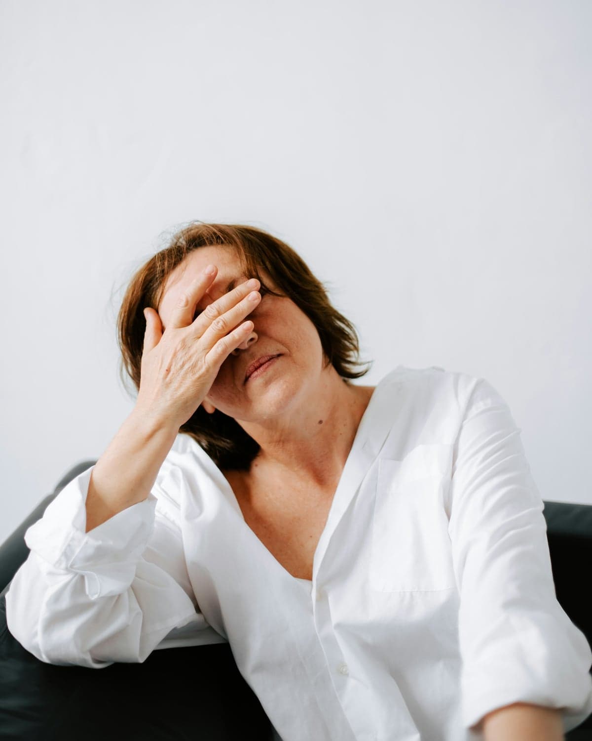 A woman sitting with her hand resting over her eyes and forehead