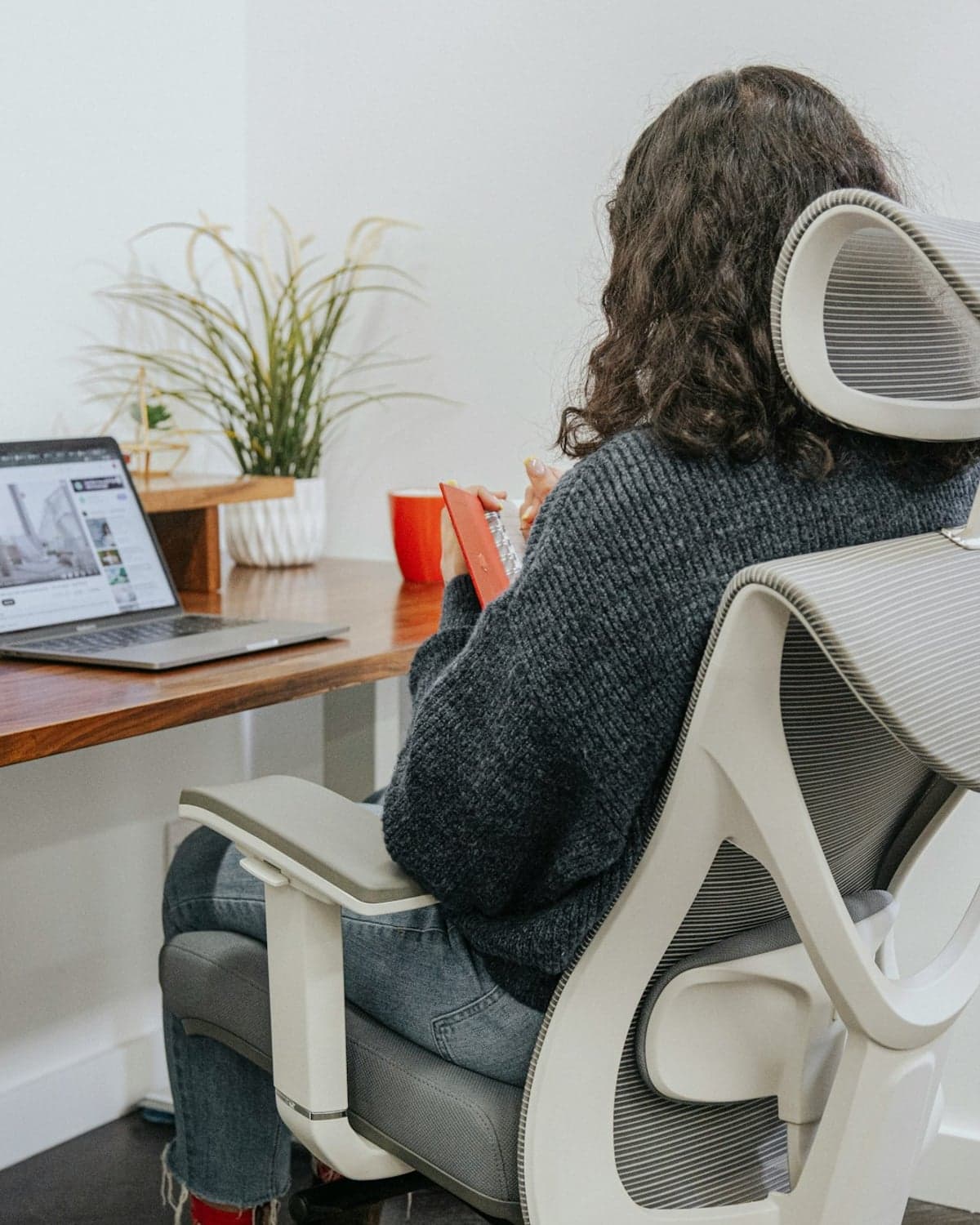 Someone working at a laptop in an office chair, seen from behind