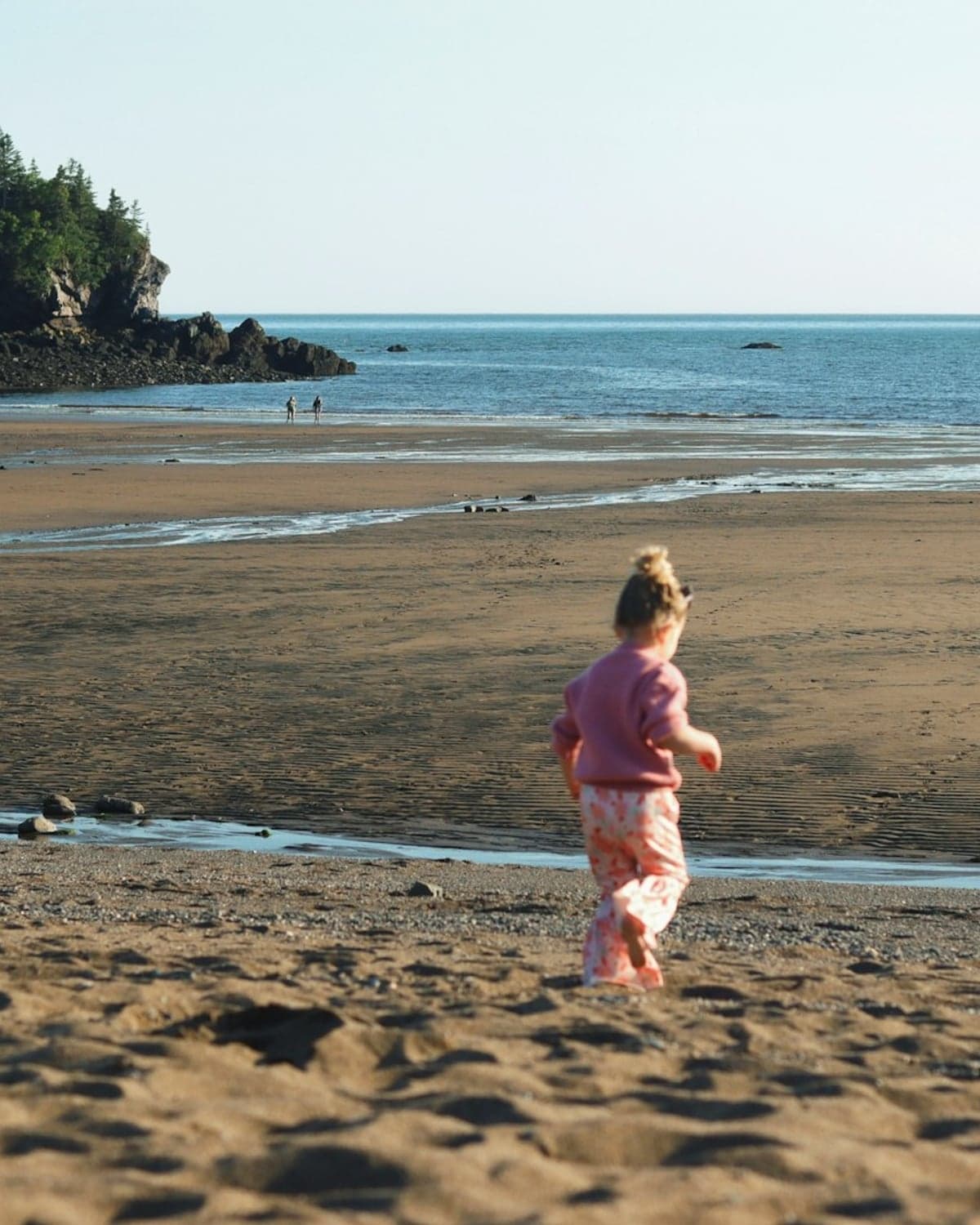A child running freely on a New England coastal beach