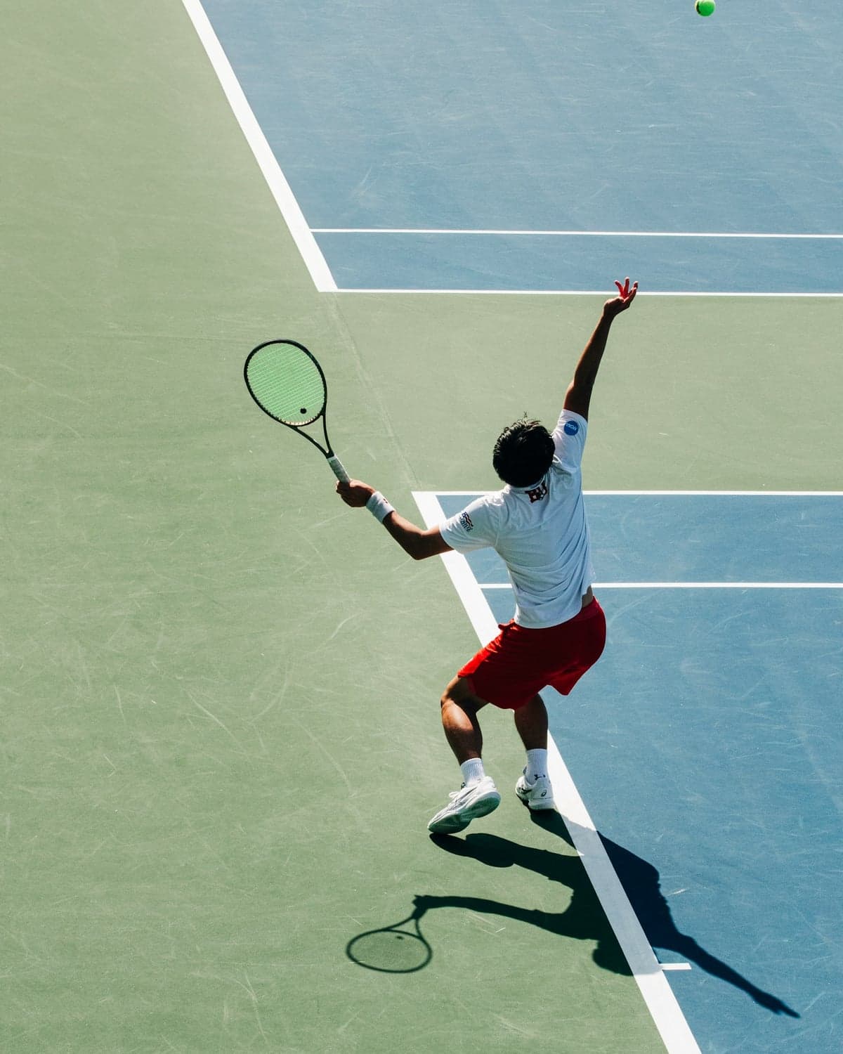 Aerial view of a tennis player launching into a serve